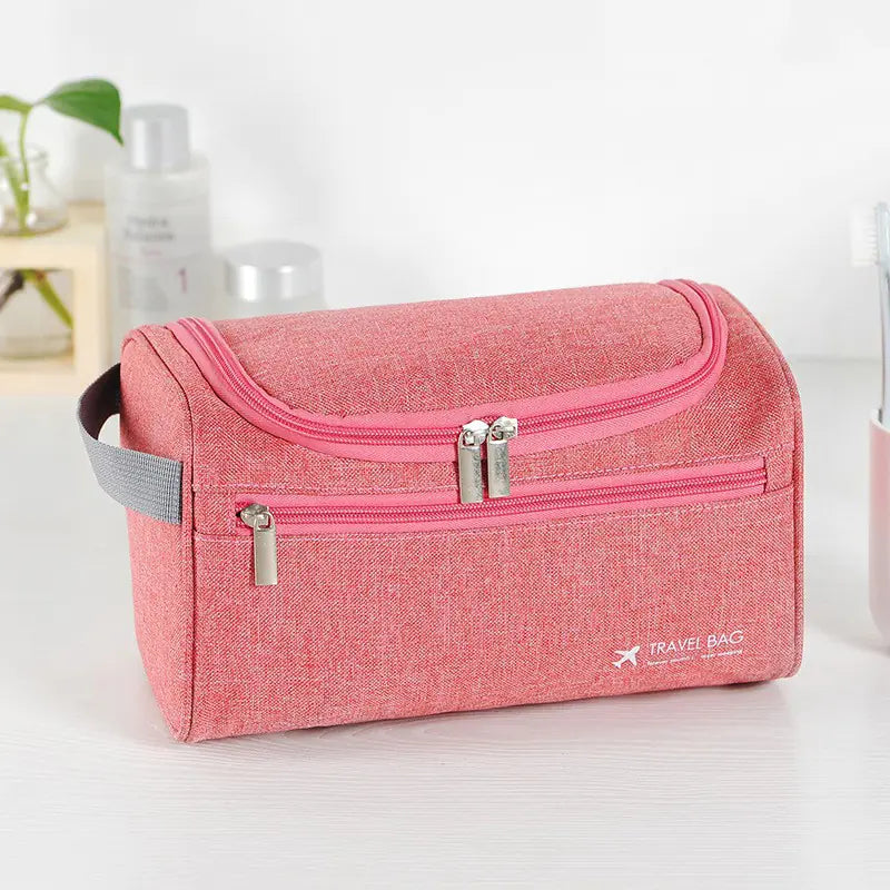 Elegant rosa toalettveske med konvoluttdesign, magnetisk lukking og justerbar skulderstropp – perfekt for å holde orden på toalettsaker og sminke under reisen.