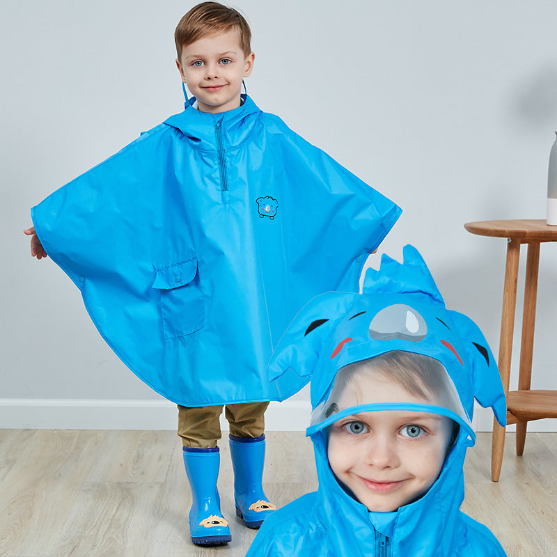 Barn med blå regnponcho og matchende regnstøvler smiler inn i kameraet. Ponchoen har hette med morsomt dyredesign og gir full beskyttelse mot regn.