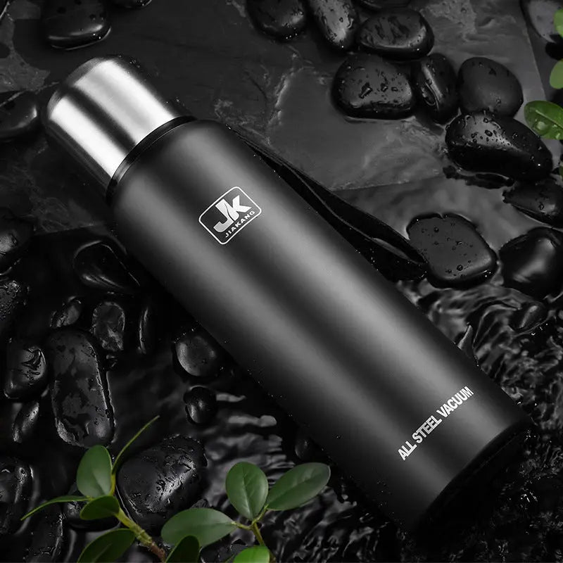 Svart termos i rustfri stål med isolerende egenskaper, designet for å holde drikkevarer varme eller kalde i flere timer. Den har en praktisk skrulokk og en slank, moderne form som gjør den enkel å bære med seg.