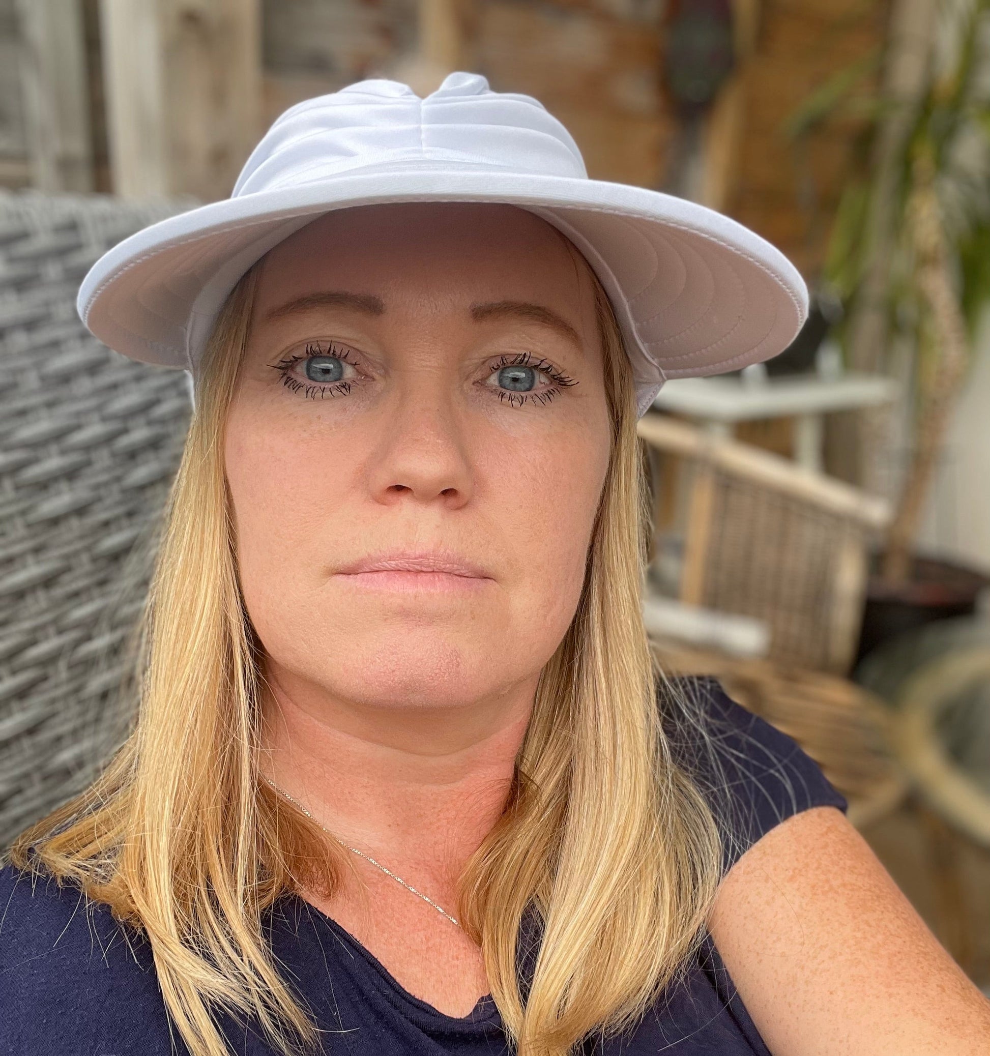 Kvinne med blondt hår iført trendy hvit solhatt med bred brem, perfekt for solfylte dager. Hatten kombinerer stil og solbeskyttelse, ideell for tur, strand og hagebruk.

