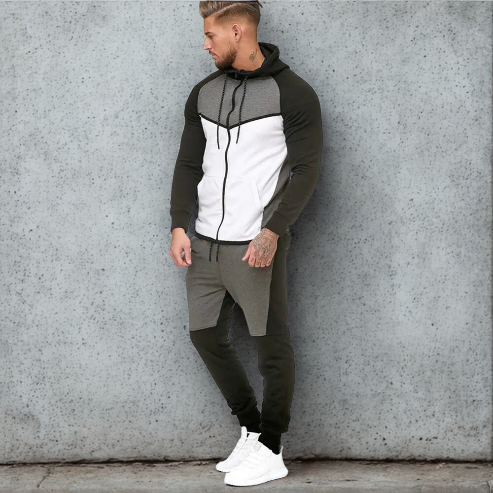 Komfortabelt sports treningssett for menn, bestående av hettegenser og joggebukse i grått, hvitt og mørkegrønt, vist på en modell mot betongbakgrunn.