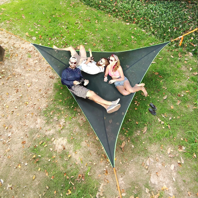 Bærbar trekantet hengekøye i pustende mesh-materiale, opphengt mellom tre trær med solide stropper og D-ringer. Hengekøyen svever over bakken og gir plass til flere personer, perfekt for camping, hage eller tur.

